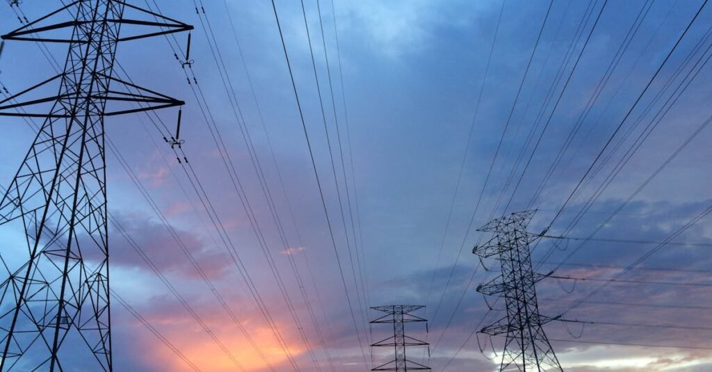 A scenic view of high voltage power lines silhouetted against a vibrant sunset sky.